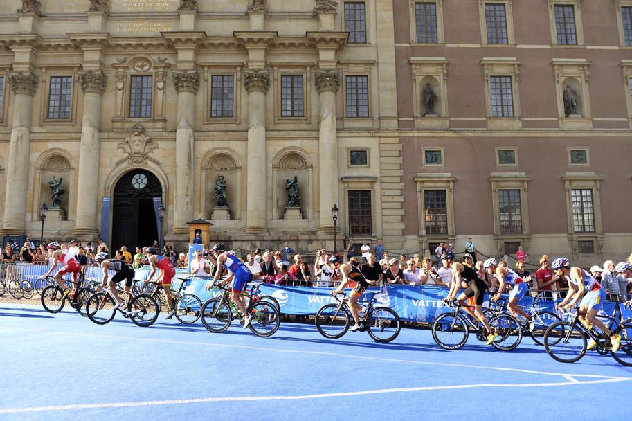 Triatlete in gara nella prova di ciclismo transitano di fronte al Palazzo Reale di Stoccolma (Afp)
